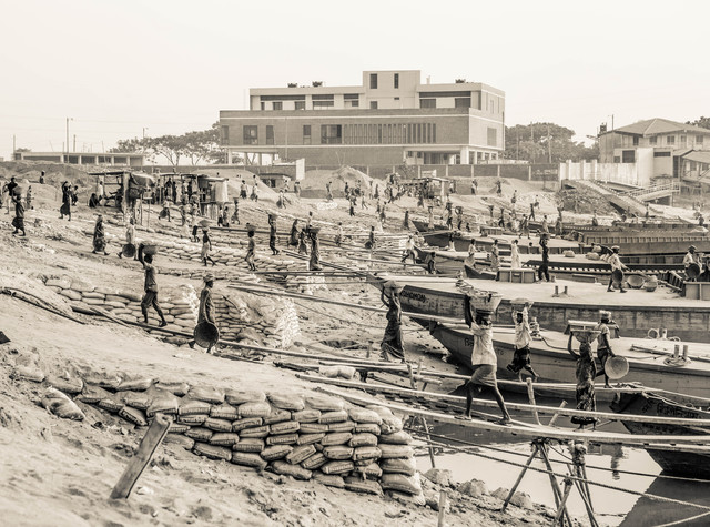 Ameisen von Timo Keitel - Billiglohnarbeiter entladen Sand von am Ufer liegenden Frachtschiffen