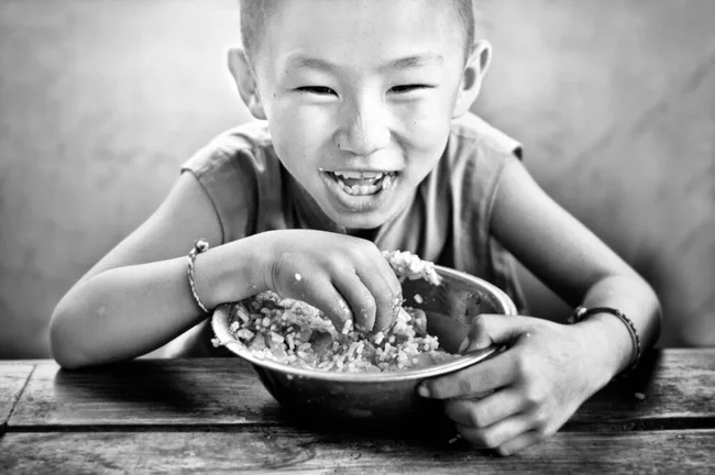 Schwarz-weiß Portrait eines jungen Mönchs beim Mittagessen von Victoria Knobloch
